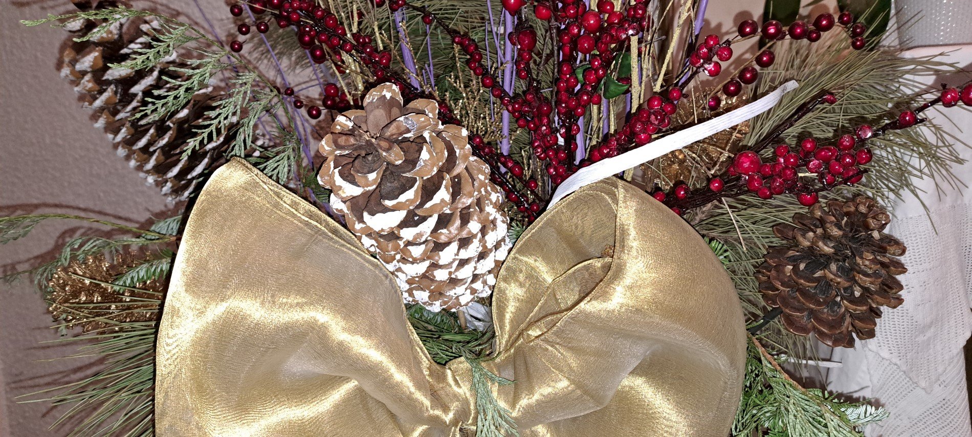 Picture of planter in front of the tabernacle with gold satin bough, tree branches, gold sticks, picks with red berries, and pine cones