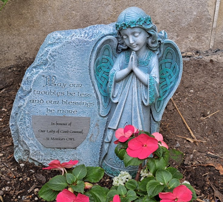 Picture of angel statue placed by the CWL in the parish garden with words "May our troubles be less and our blessings be more" and a plaque that says "In honour of Our Lady of Good Counsel St. Monica's CWL"