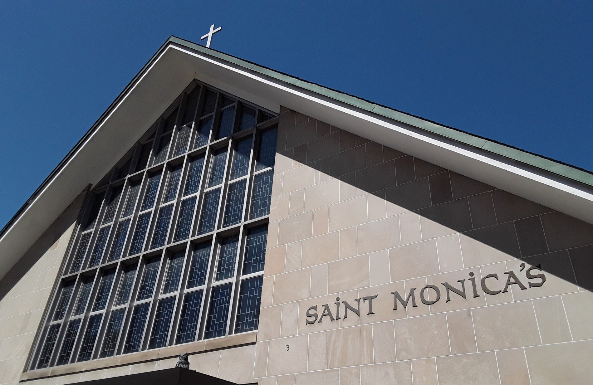 Picture showing words St. Monica's written on front of church, stained glass window, and cross on roof