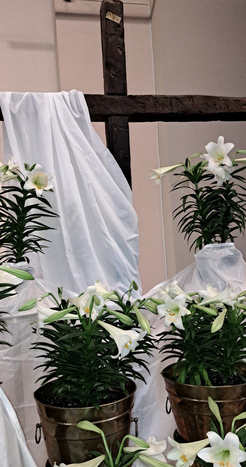 Picture of brown cross draped in white with lilies