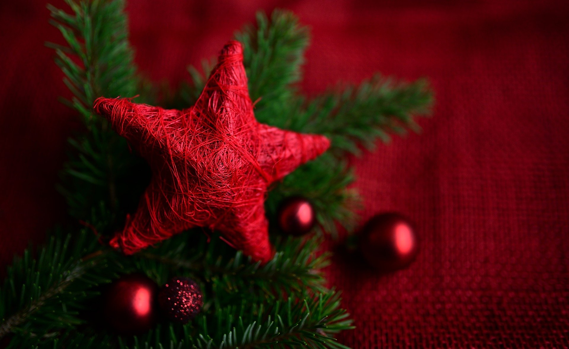 Picture of red cloth shaped like a star with greenery and red balls in the background